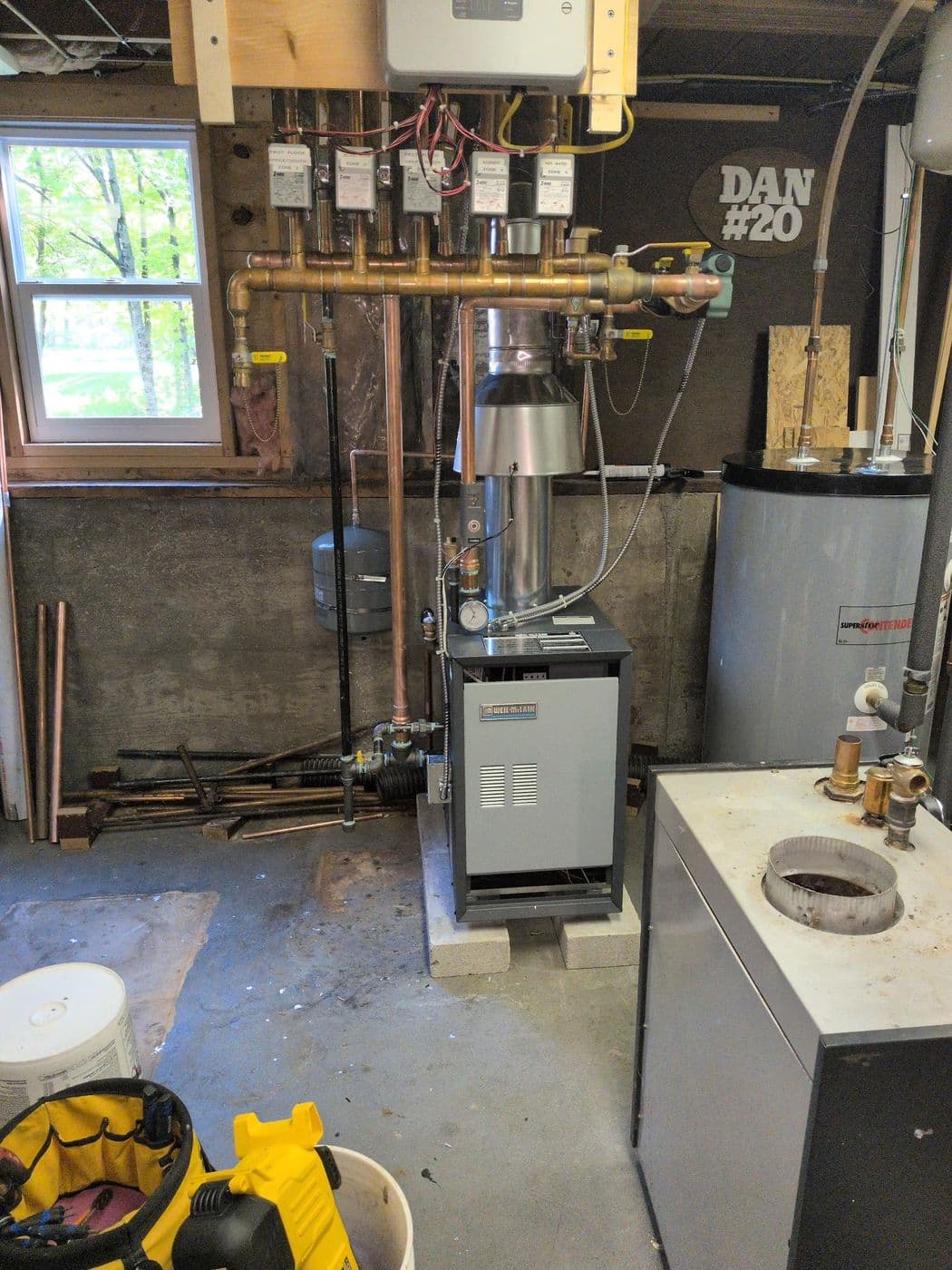 White floor-mounted heat pump console installed against a wall in a finished room with hardwood floors